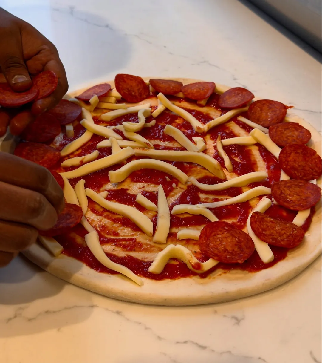 Pepperoni being laid onto a pizza.