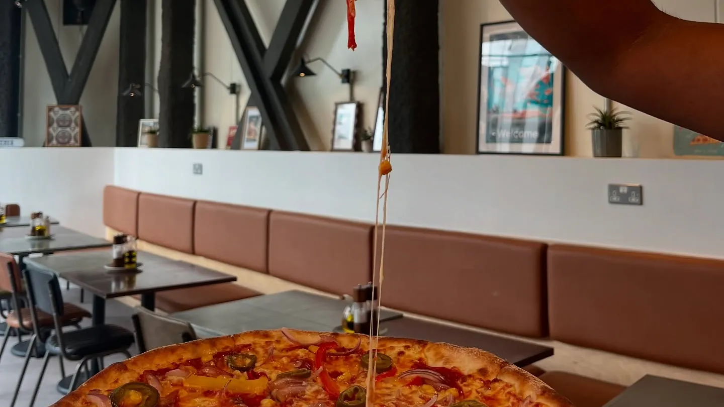 A slice of pizza pulled high above the table in our Canary Wharf restaurant.