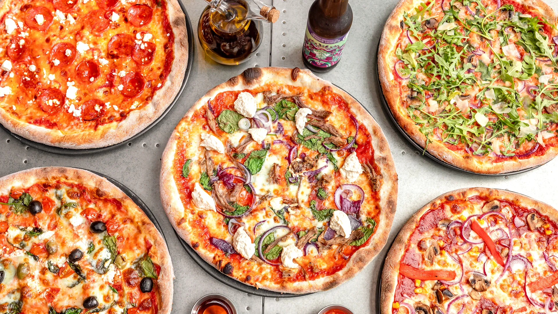 A spread of @homepizza pizzas on a steel table.